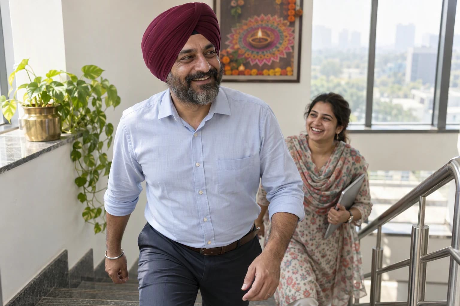 A man in a turban grins as he takes the office stairs with a colleague